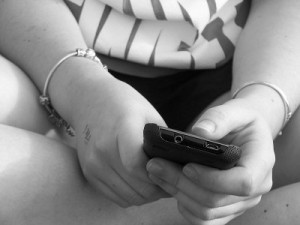 imagen de las manos de una adolescente con un teléfono móvil